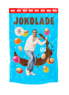 Produktverpackung (blau): JOKOLADE Peanuts mit Salz. Joko Winterscheidt steht in der Mitte und zeigt auf eine dragierte Erdnuss. Hintergrund: "fliegende" dragierte Erdnüsse. Button: Approved by Joko Winterscheidt. Faire Schokolade. Banderole oben: rot: NEU
