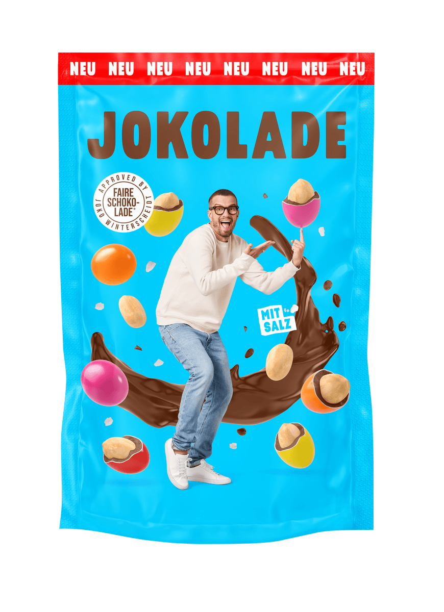 Produktverpackung (blau): JOKOLADE Peanuts mit Salz. Joko Winterscheidt steht in der Mitte und zeigt auf eine dragierte Erdnuss. Hintergrund: "fliegende" dragierte Erdnüsse. Button: Approved by Joko Winterscheidt. Faire Schokolade. Banderole oben: rot: NEU